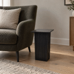 Black wooden carved base end table beside a lounge chair in a contemporary living room