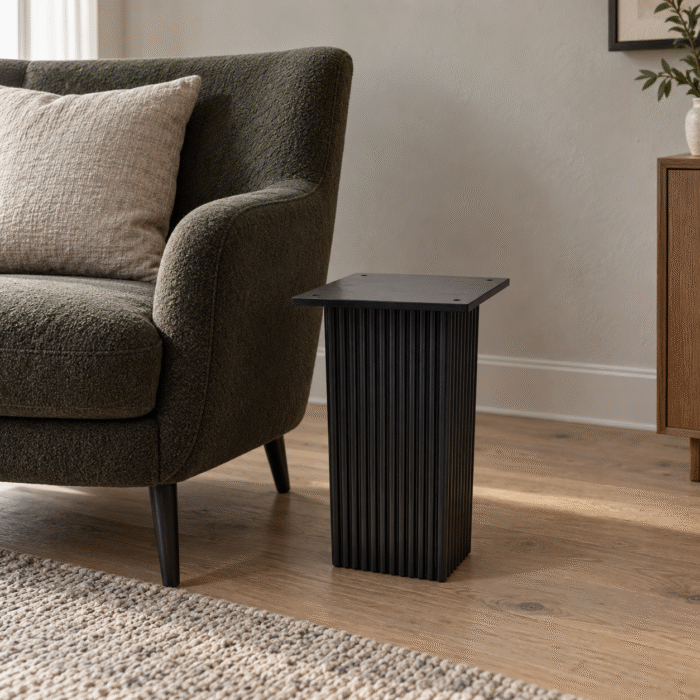 Black wooden carved base end table beside a lounge chair in a contemporary living room