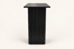 Black wooden carved base end table on warm ivory background