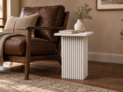 White wooden carved end table beside a leather lounge chair in a contemporary living room