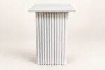 White wooden carved base end table on warm ivory background