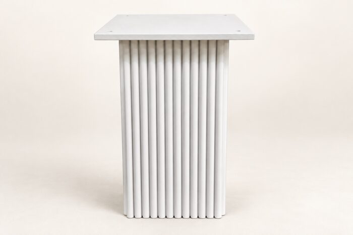 White wooden carved base end table on warm ivory background