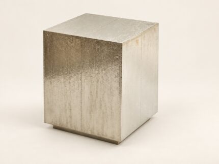 Hammered metal cladded end table on warm ivory background