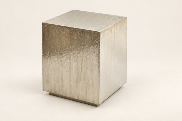Hammered metal cladded end table on warm ivory background