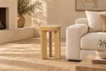Travertine Alta Side Table with three legs beside a cream sofa in a warm neutral living room