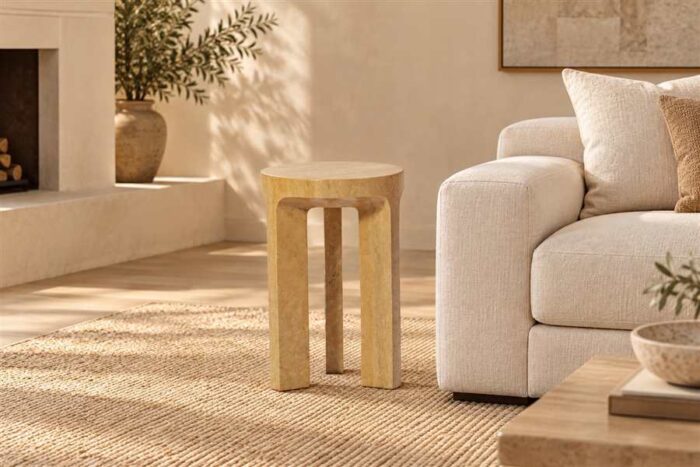 Travertine Alta Side Table with three legs beside a cream sofa in a warm neutral living room